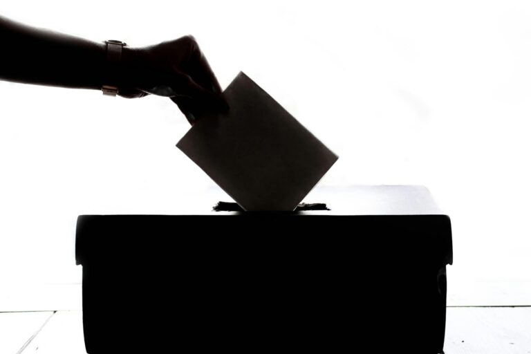Person dropping a piece of paper in a ballot box